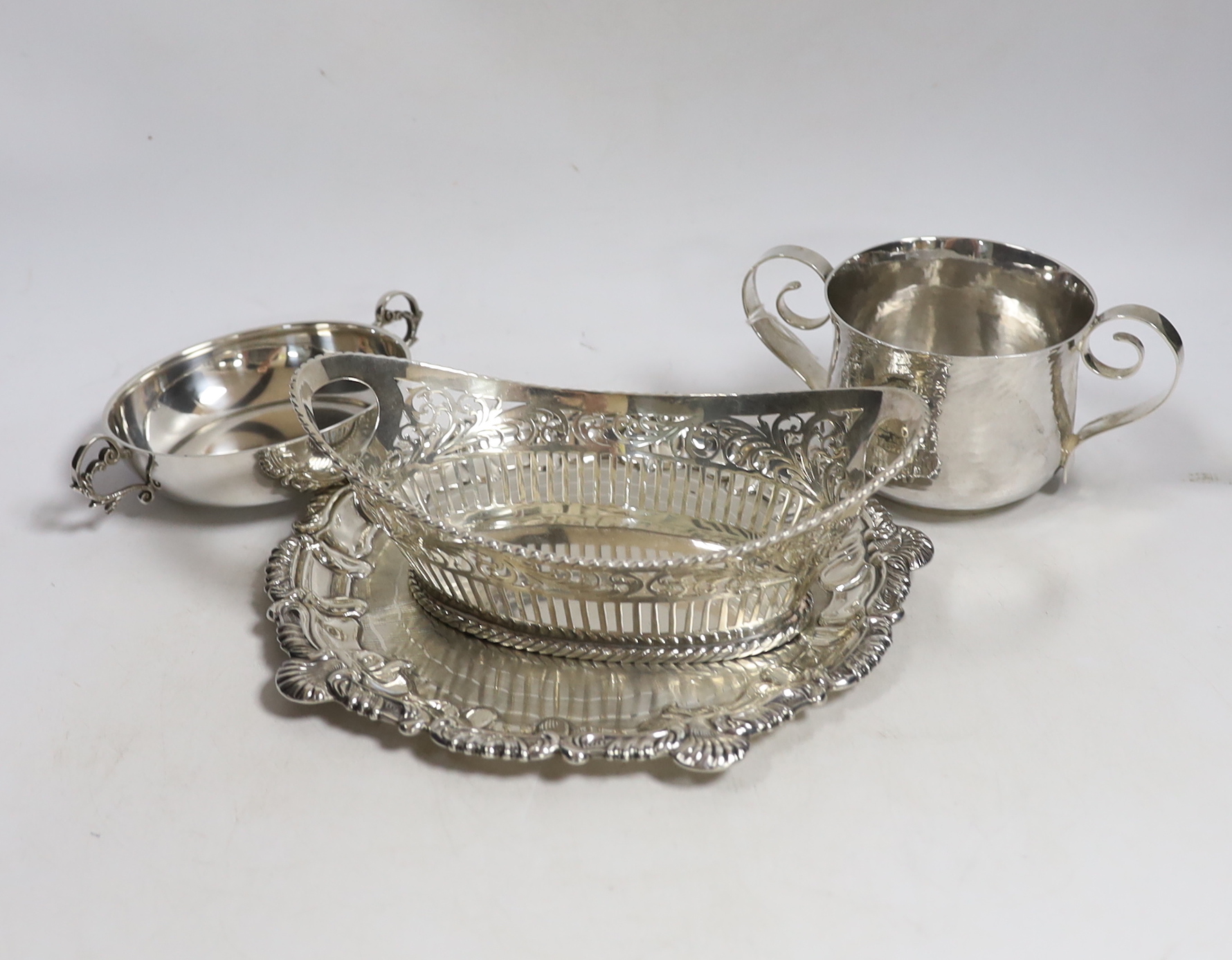 An Edwardian planished Britannia standard silver two handled cup, by Daniel & John Welby, London, 1902, height 77mm, together with a silver shallow two handled dish, a pierced silver oval dish and a silver waiter, 24.4oz